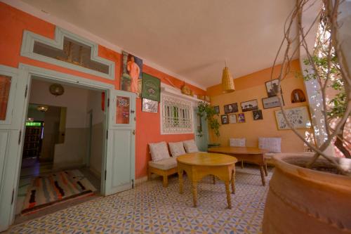 a living room with orange walls and a table at Maison d'hôtes Dar Farhana in Ouarzazate