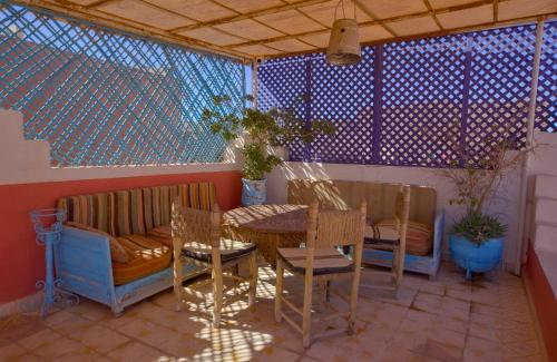 a patio with a table and chairs and a couch at Maison d'hôtes Dar Farhana in Ouarzazate