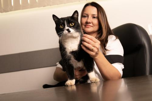 a woman sitting at a table holding a black and white cat at Tezla Hotel in Primavera do Leste