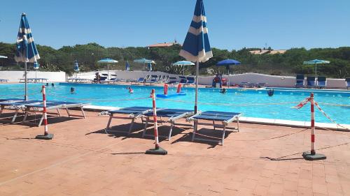 een groot zwembad met stoelen en parasols bij Villa Marina con piscina sul mare in Platamona