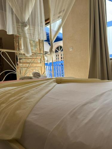 a close up of a bed with white sheets and curtains at Dar Halima in Essaouira
