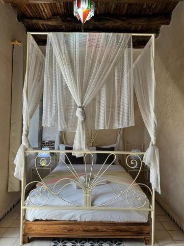 a canopy bed with white curtains on it at Dar Halima in Essaouira