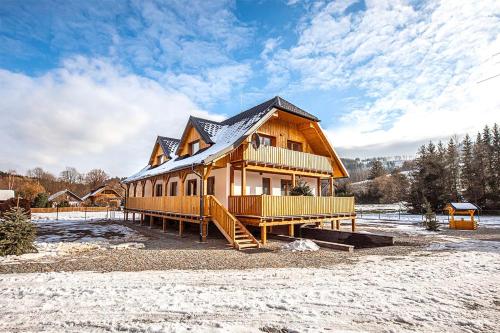 a large wooden house with a gambrel roof in the snow at Chalupa U Myslivce in Dolní Lomná
