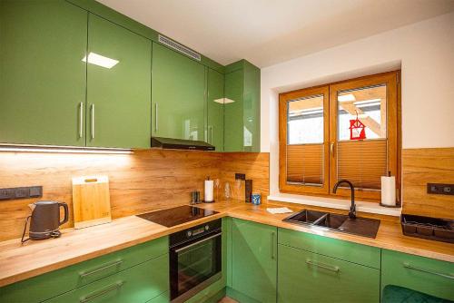 a kitchen with green cabinets and a wooden counter top at Chalupa U Myslivce in Dolní Lomná