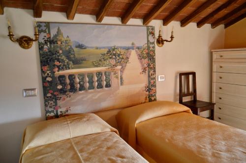 a bedroom with two beds and a painting on the wall at Agriturismo Il Caggio in Sovicille