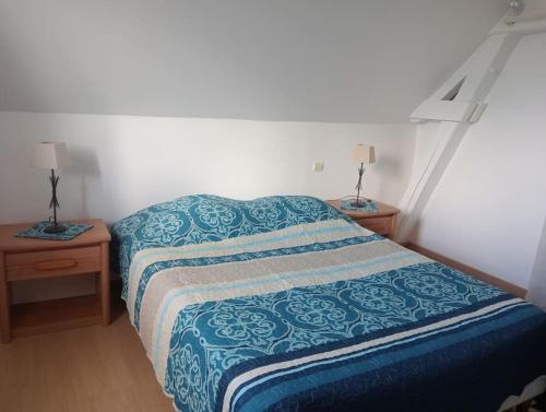 ein Schlafzimmer mit einem Bett mit einer blauen Decke und 2 Tischen in der Unterkunft maison de campagne au calme, Le Lude in Le Lude