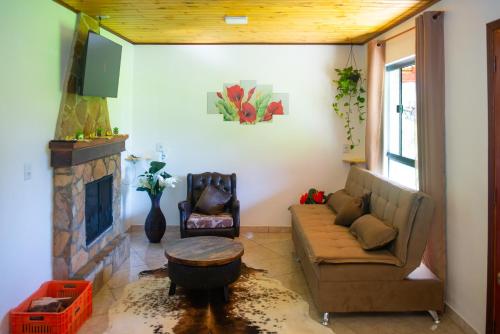 a living room with a couch and a fireplace at Chalés Cachoeira do Vale in Camanducaia