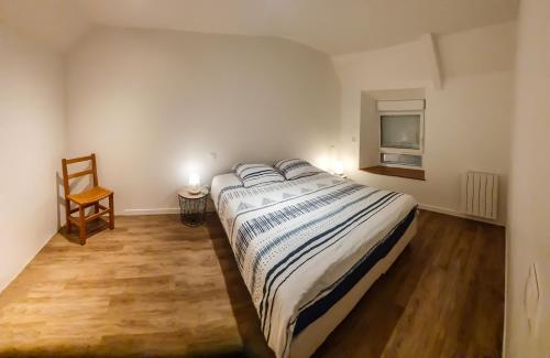 een slaapkamer met een bed, een stoel en een raam bij La Grange in Bretteville