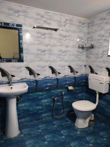 a bathroom with a sink and dolphins on the wall at Lucy Guest House in Bogmalo