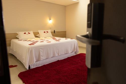 a bedroom with a white bed with a red rug at Tezla Hotel in Primavera do Leste