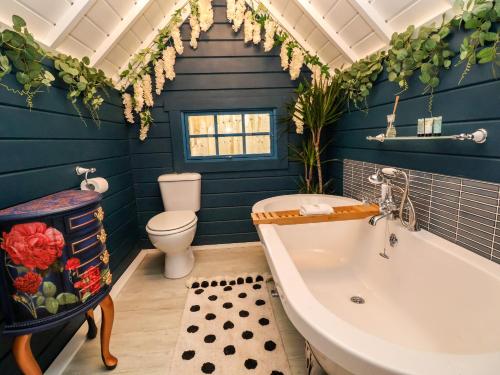 uma casa de banho com paredes azuis, uma banheira e um WC. em Applejacks Orchard em Holywell