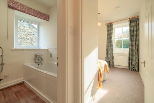 uma casa de banho com uma banheira, uma cama e uma janela em Townend Farmhouse - Ullswater em Watermillock