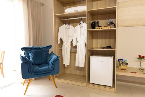 a living room with a blue chair and a closet at Tezla Hotel in Primavera do Leste