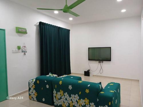 a living room with a blue couch and a flat screen tv at Ees Green Homestay Meru Klang in Kapar