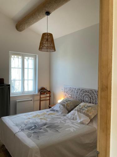 - une chambre avec un lit et une lampe pendant dans l'établissement La jasse, à Cabrières-dʼAigues
