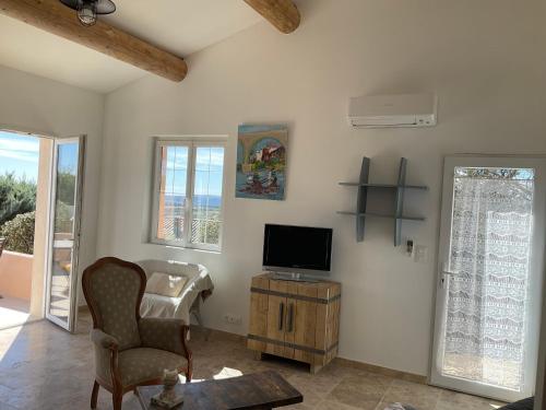 ein Wohnzimmer mit Fernseher und Sessel in der Unterkunft La jasse in Cabrières-dʼAigues