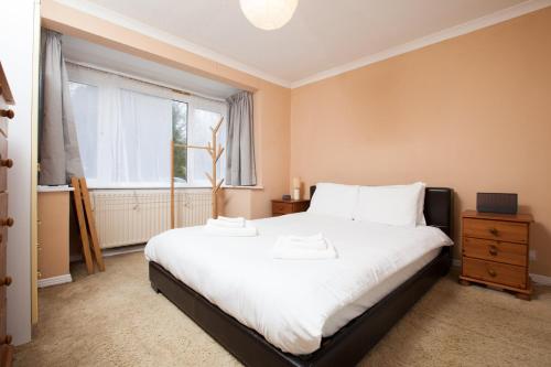 um quarto com uma grande cama branca e uma janela em GuestReady - Spacious 2BR Flat in Peaceful Hove em Brighton & Hove