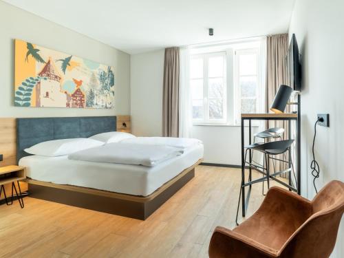 um quarto de hotel com uma cama e uma cadeira em B&B HOTEL Albstadt-Hbf em Albstadt