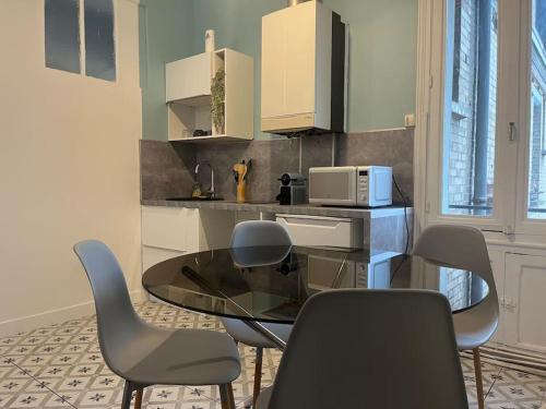 une cuisine avec une table et des chaises en verre dans l'établissement Appartement cœur de ville, à Soissons
