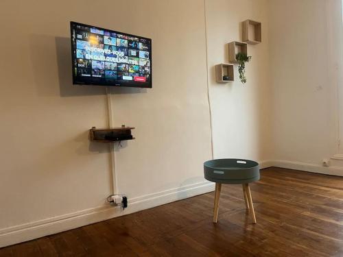a room with a tv on a wall with a stool at Appartement cœur de ville in Soissons