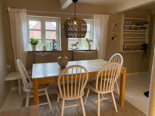 a dining room table with four chairs and aendant light at Sofie's Hus - Munkgaard in Hårlev