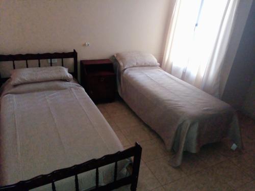 two beds in a small room with a window at Casa en Chilecito equipada cerca ruta 40 in Chilecito