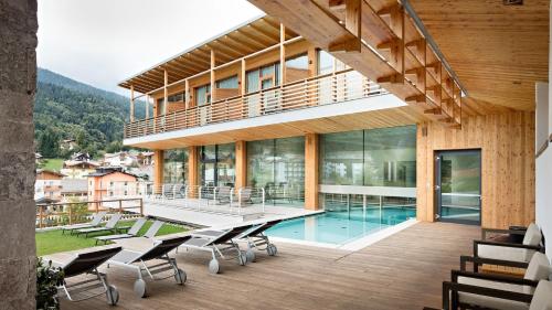 a house with a pool and a deck with chairs at Corona Dolomites Hotel in Andalo