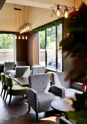 a waiting room with chairs and tables and windows at Abbey Hotel in Leicester