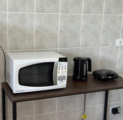 a microwave sitting on a shelf next to a coffee pot at Lemon Suítes e Pousada - Indaiá Riviera in Bertioga