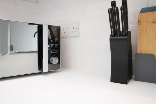 a microwave on a counter next to a knife block at 2 Bed Flat near Stadium with Street Parking by CTO Serviced Apartments in Cardiff