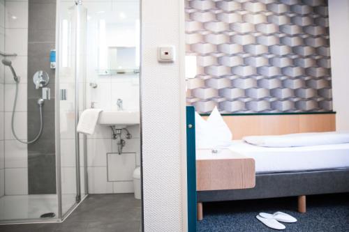 La salle de bains est pourvue d'une baignoire, d'un lavabo et d'une douche. dans l'établissement Hotel Regina, à Wurtzbourg