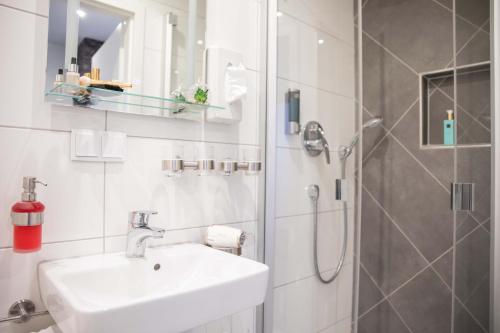 a white bathroom with a sink and a shower at Hotel Regina in Würzburg