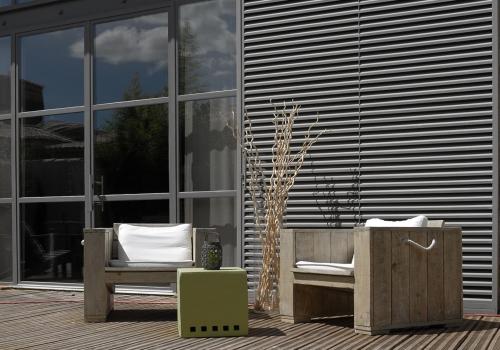 a patio with a bench and a chair in front of a building at Le Mas Des Brunes in Saint-Laurent-dʼAigouze