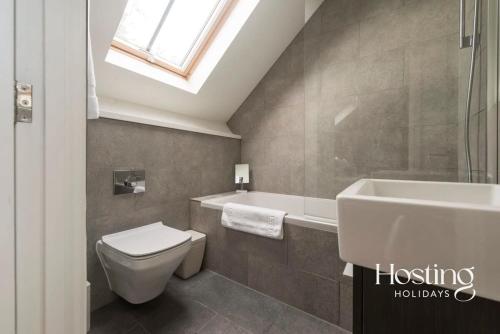 a bathroom with a toilet and a tub and a sink at The Henley Retreat in Henley on Thames