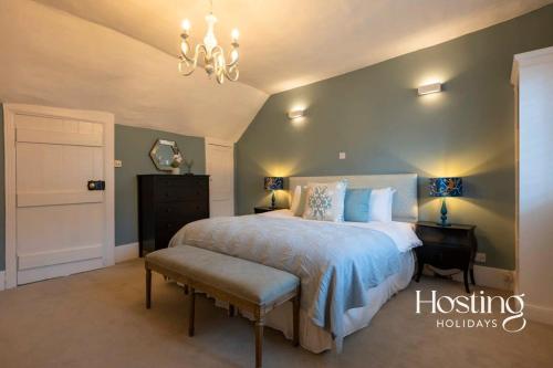 Un dormitorio con una cama grande y una lámpara de araña. en Spacious Luxury Cottage With Roof Terrace Close To The River Thames en Henley on Thames