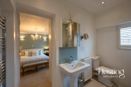 1 dormitorio con 1 cama y baño con lavabo. en Spacious Luxury Cottage With Roof Terrace Close To The River Thames en Henley on Thames