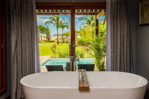 a bath tub in a bathroom with a view of a pool at Pousada Mi Secreto in São Miguel do Gostoso