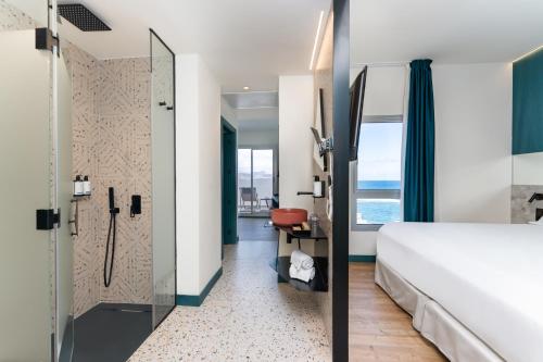 um quarto de hotel com uma cama e um chuveiro em Occidental Las Canteras em Las Palmas de Gran Canaria