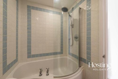 a bathroom with a tub with a shower and a sink at Stunning Character House In The Centre of Henley in Henley on Thames