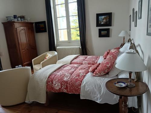 a bedroom with a bed and a table with a lamp at Castel La Bergerie in Laglorieuse