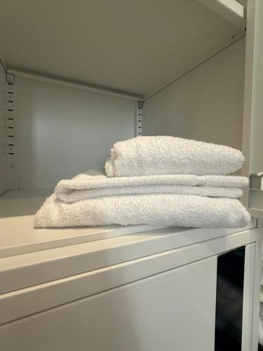 una pila de toallas blancas sentadas en un estante en Hostel Alicante A-cero Living, en Alicante