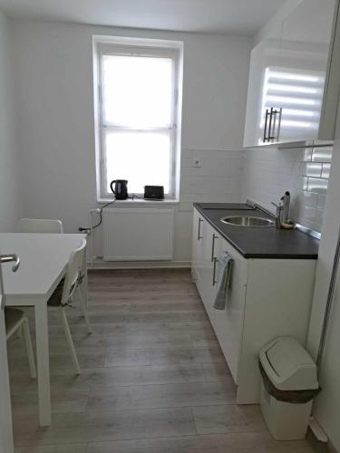 a kitchen with a sink and a table and a window at Tarcal Apartman in Tarcal