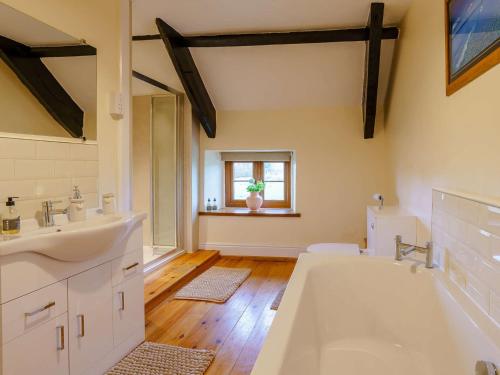 uma casa de banho com 2 lavatórios, uma banheira e uma janela em 4 Bed in Abergavenny 88014 em Llanover