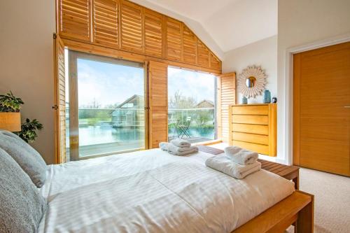 1 dormitorio con cama y ventana grande en Waters Edge 15, Kingsholm P en South Cerney