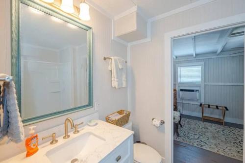 a bathroom with a sink and a toilet and a mirror at The Cottage - Downtown Rockport in Rockport