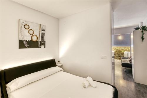 エンプリアブラバにあるPANORAMIC D-LUXEの白いベッドと壁の絵が備わるベッドルーム1室が備わります。