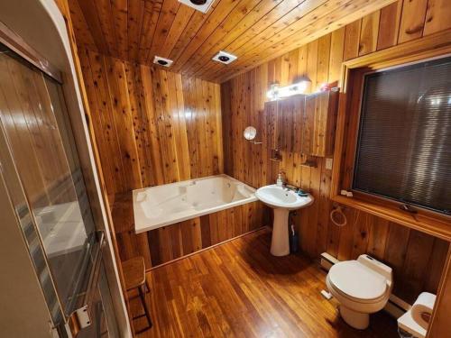 y baño con bañera, aseo y lavamanos. en Private Rustic Lodge w/ Lakefront Views en Minden