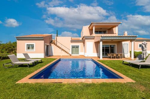 a villa with a swimming pool in front of a house at Vale da Lapa Village Resort in Carvoeiro