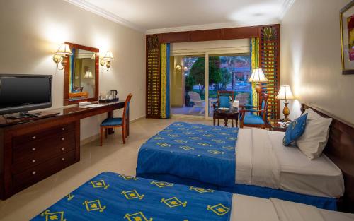 a hotel room with a bed and a desk and a television at Caribbean World Resort Soma Bay in Hurghada