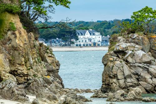 a view of a rocky shore with a house in the background at Garrigae Cap Coz in Fouesnant